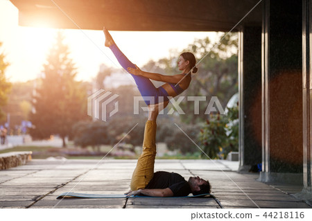 Young man and woman practicing acro yoga on street Young man and woman practicing acro yoga on street 44218116