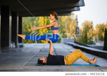 Young man and woman practicing acro yoga on street Young man and woman practicing acro yoga on street 44218118