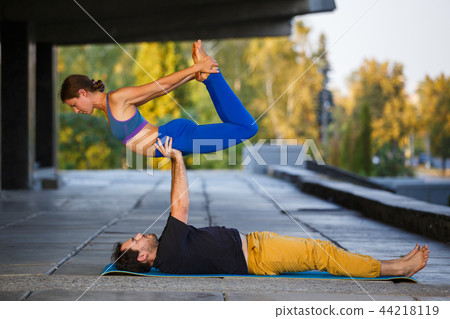 Young man and woman practicing acro yoga on street Young man and woman practicing acro yoga on street 44218119