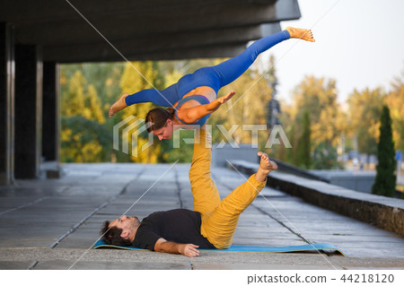 Young man and woman practicing acro yoga on street Young man and woman practicing acro yoga on street 44218120