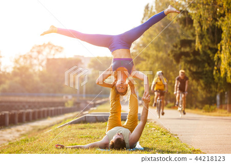 Couple of young man and woman practicing acro yoga Couple of young man and woman practicing acro yoga 44218123