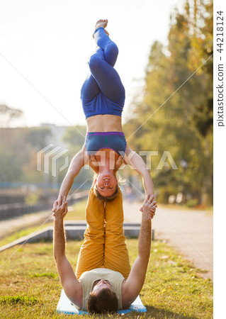 Couple of young man and woman practicing acro yoga 44218124