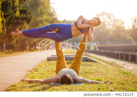 Couple of young man and woman practicing acro yoga 44218125