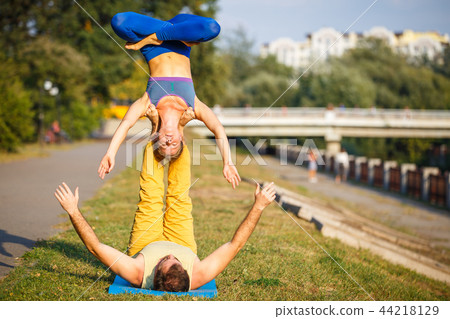 Couple of young man and woman practicing acro yoga 44218129