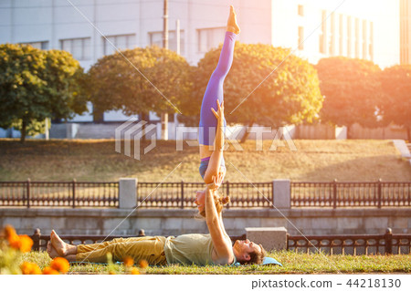 Couple of young man and woman practicing acro yoga Couple of young man and woman practicing acro yoga 44218130