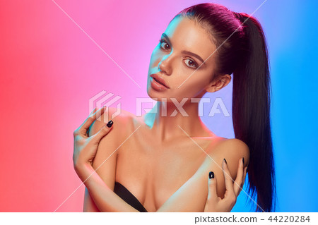 High Fashion model woman in colorful bright lights posing in studio 44220284