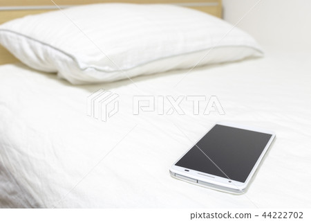智能手機操作的圖像在床上的 智能手機操作的圖像在床上的 44222702
