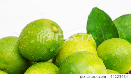 Green lime in a basket on a white wooden table. 44225484