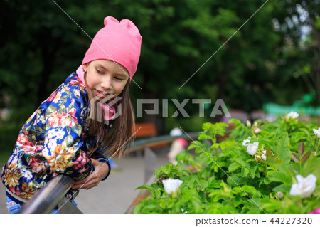 Beautiful kid girl with long hair in rose cap smiling outdoors. Beautiful kid girl with long hair in rose cap smiling outdoors. 44227320