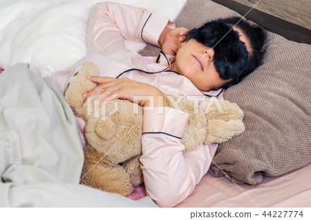 Beautiful woman in sleeping mask and toy bunny in Beautiful woman in sleeping mask and toy bunny in 44227774