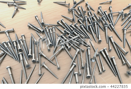 Many different screws on wooden table 44227835