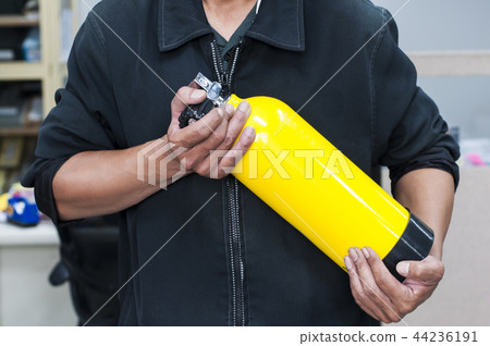 Unidentified people holding yellow oxygen tank. Unidentified people holding yellow oxygen tank. 44236191