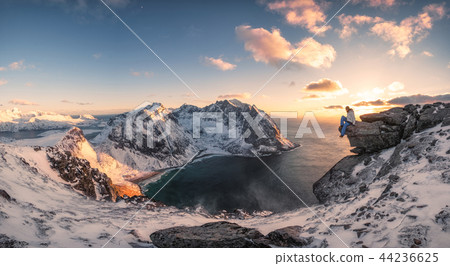 Panorama of Mountaineer sitting on rock on peak 44236625