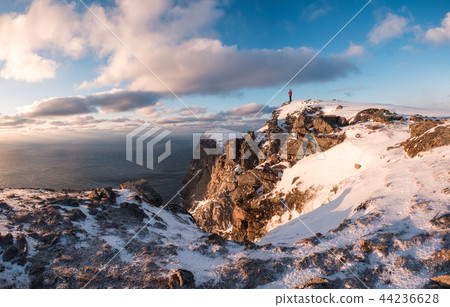 Climber standing on peak of rock mountain 44236628