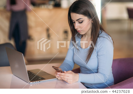 Beautiful brunette business woman use phone in a cafe with laptop 44237028