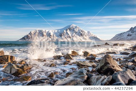 Arctic ocean wave hitting rocks with sunshine 44237294