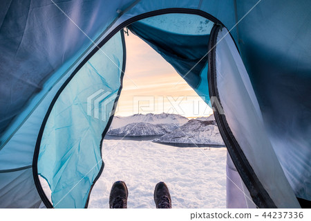 Snow boots relaxing inside tent camping entrance Snow boots relaxing inside tent camping entrance 44237336