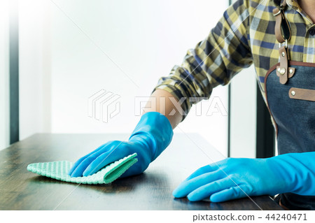 man with cloth cleaning wooden table in home uses rag and fluid 44240471
