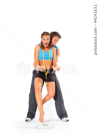 Young man lifting woman above weighing scale 44241631
