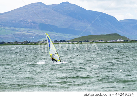 Man windsurfing close to the town of Caernarfon in Wales - United Kingdom Man windsurfing close to the town of Caernarfon in Wales - United Kingdom 44249154