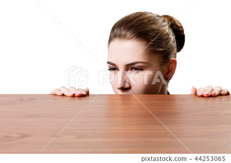 Woman peeping under the edge of wooden table. Woman peeping under the edge of wooden table. 44253065