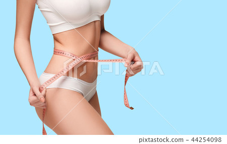 The girl taking measurements of her body, blue background. The girl taking measurements of her body, blue background. 44254098