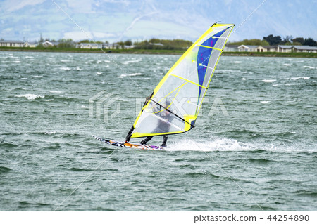 Man windsurfing close to the town of Caernarfon in Wales - United Kingdom Man windsurfing close to the town of Caernarfon in Wales - United Kingdom 44254890