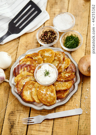 metal plate with delicious potato pancakes on an old wooden table with bowls full of additions 44255162