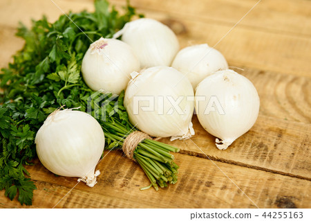 white fresh onion and a bunch of parsley on an old wooden table white fresh onion and a bunch of parsley on an old wooden table 44255163