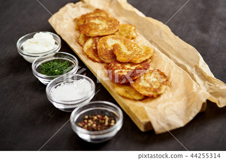 delicious potato pancakes and bowls with additions on an old wooden black table delicious potato pancakes and bowls with additions on an old wooden black table 44255314