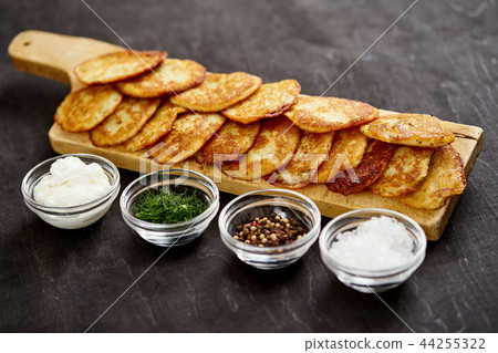 delicious potato pancakes and bowls with additions on an old wooden black table 44255322