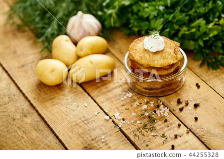 small bowl with potato pancakes on an old wooden table with garlic and parsley 44255328