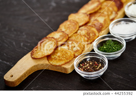 delicious potato pancakes and bowls with additions on an old wooden black table delicious potato pancakes and bowls with additions on an old wooden black table 44255392