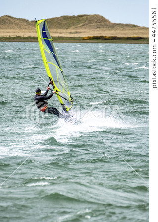 Man windsurfing close to the town of Caernarfon in Wales - United Kingdom Man windsurfing close to the town of Caernarfon in Wales - United Kingdom 44255561