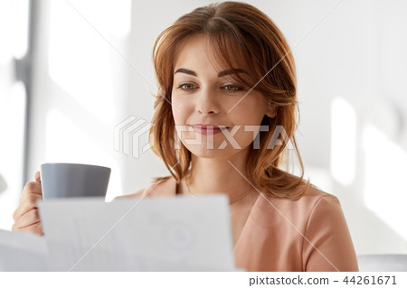 businesswoman with papers drinks coffee at office 44261671