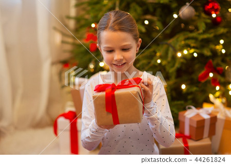 smiling girl with christmas gift at home smiling girl with christmas gift at home 44261824