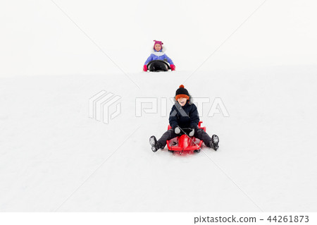 happy kids sliding on sleds down hill in winter 44261873