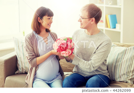 happy husband giving flowers to his pregnant wife 44262099