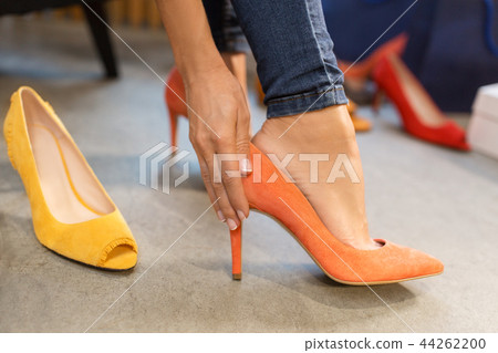 young woman trying high heeled shoes at store young woman trying high heeled shoes at store 44262200