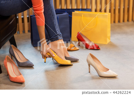 young woman trying high-heeled shoes at store 44262224