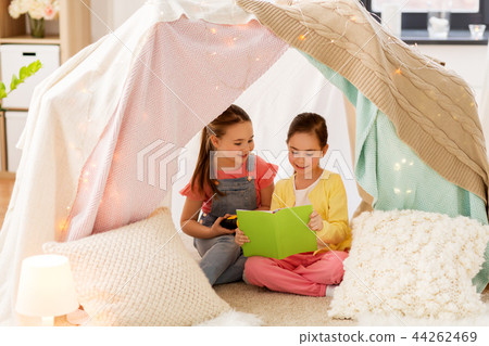little girls reading book in kids tent at home 44262469