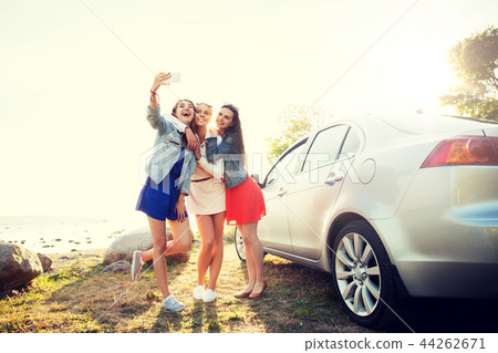 happy women taking selfie near car at seaside 44262671