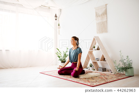 woman meditating in lotus pose at yoga studio 44262963