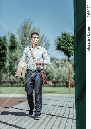 Cheerful male courier executing delivery to doorstep Cheerful male courier executing delivery to doorstep 44264071
