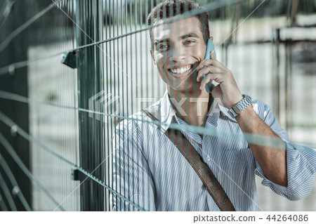 Exuberant cheerful guy gossiping vividly on phone Exuberant cheerful guy gossiping vividly on phone 44264086