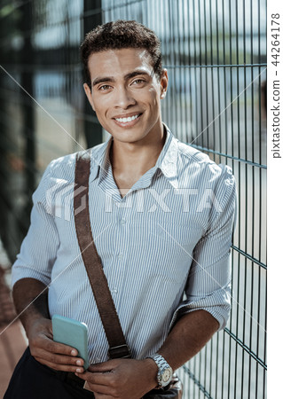 Happy jovial guy awaiting friend near fence Happy jovial guy awaiting friend near fence 44264178