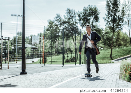Handsome male student returning from classes on skateboard 44264224