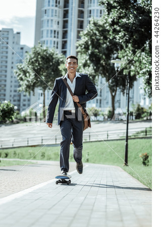 Joyful male student experimenting with his skateboard 44264230