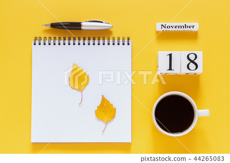 calendar November 18 cup of coffee, notepad with pen and yellow leaf on yellow background 44265083