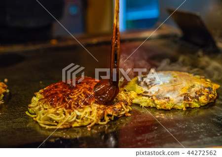 adding spicy sauce in the Okonomiyaki 44272562